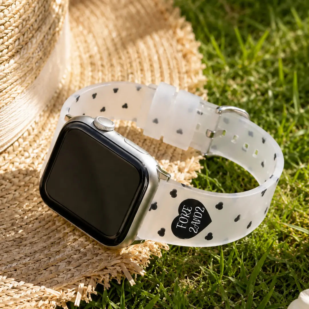 Amour clear TPU Apple Watch band with black hearts styled beside a straw hat