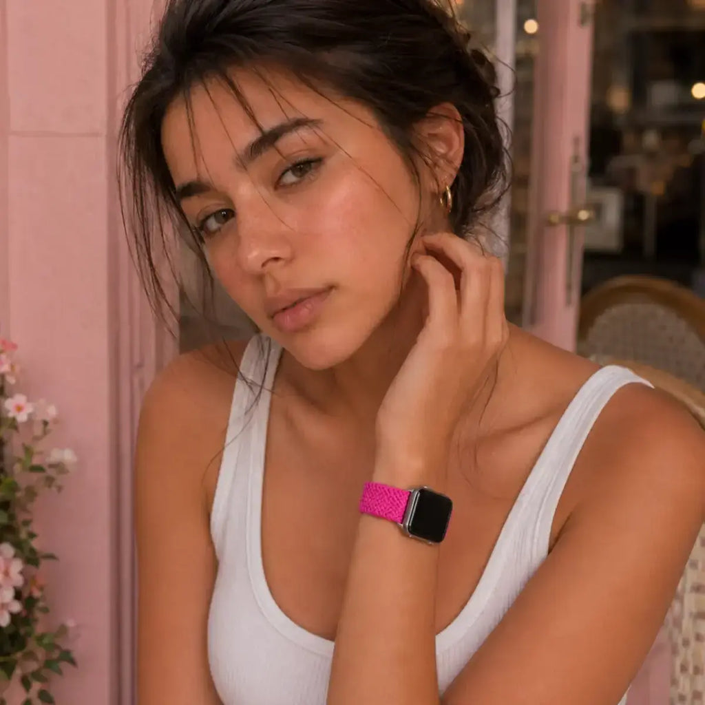 Woman wearing the Amélie fuchsia braided Apple Watch band at a pink café
