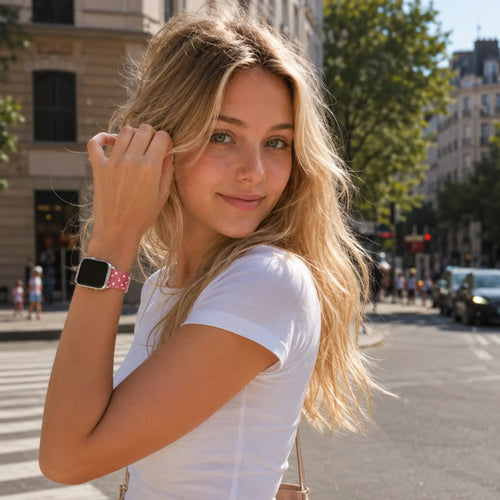 Amour pink heart Apple Watch band shown on the wrist in a natural city street portrait.