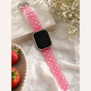 Full view of the clear pink heart Apple Watch band styled with strawberries and flowers.