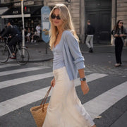 Camille blue gingham scrunchie Apple Watch band styled with a pale blue cardigan on a Paris street.
