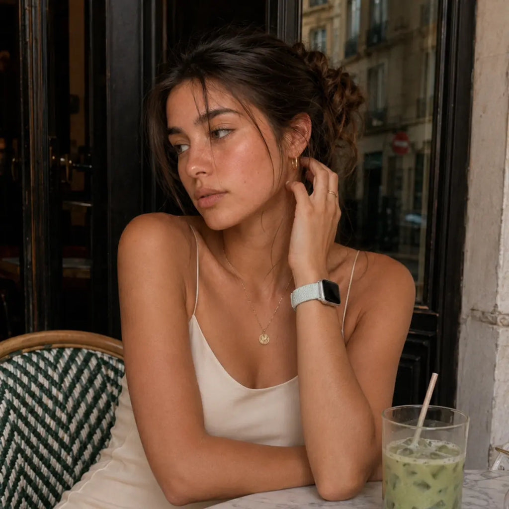 Woman wearing the Céleste mint braided loop Apple Watch band at a café