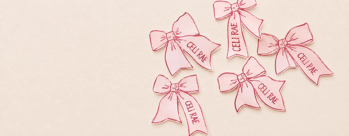 Pink CELI RAE paper bows on a clean cream background