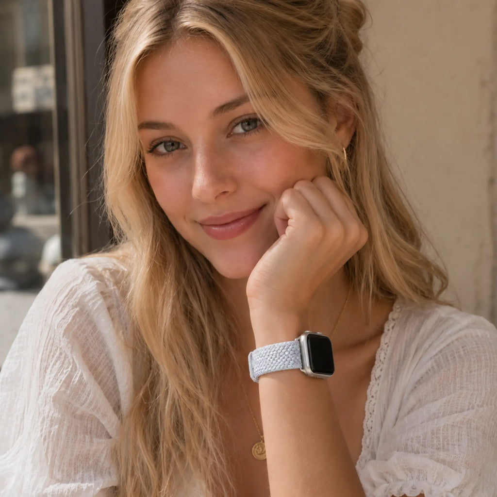 Woman wearing the Clémence blue lilac braided Apple Watch band in a café portrait.