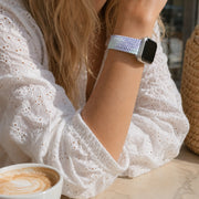 Close-up of the Clémence blue lilac braided Apple Watch band worn with a white eyelet blouse.