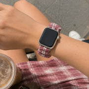 Close-up of the Élise burgundy gingham scrunchie Apple Watch band worn on the wrist.