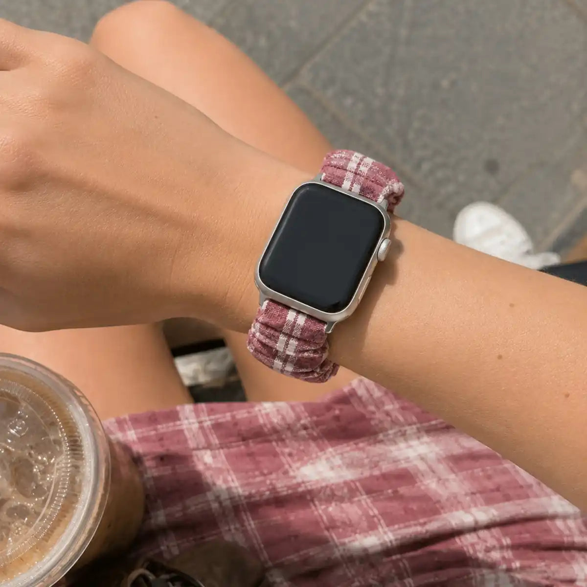 Close-up of the Élise burgundy gingham scrunchie Apple Watch band worn on the wrist.