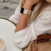 Close-up of the Margaux blush braided loop Apple Watch band at a café