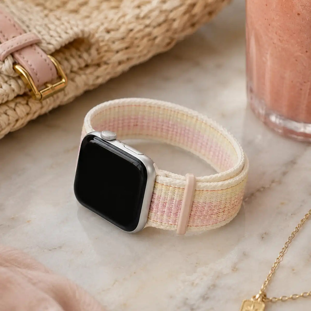 Rosalie pastel woven loop Apple Watch band displayed with a pink smoothie and woven accessories.