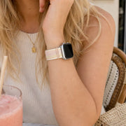 Close-up of the Rosalie pastel woven loop Apple Watch band worn at a café table.