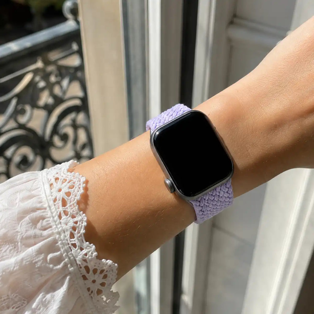 Close-up of the Soline lavender braided loop Apple Watch band worn beside a sunlit window.