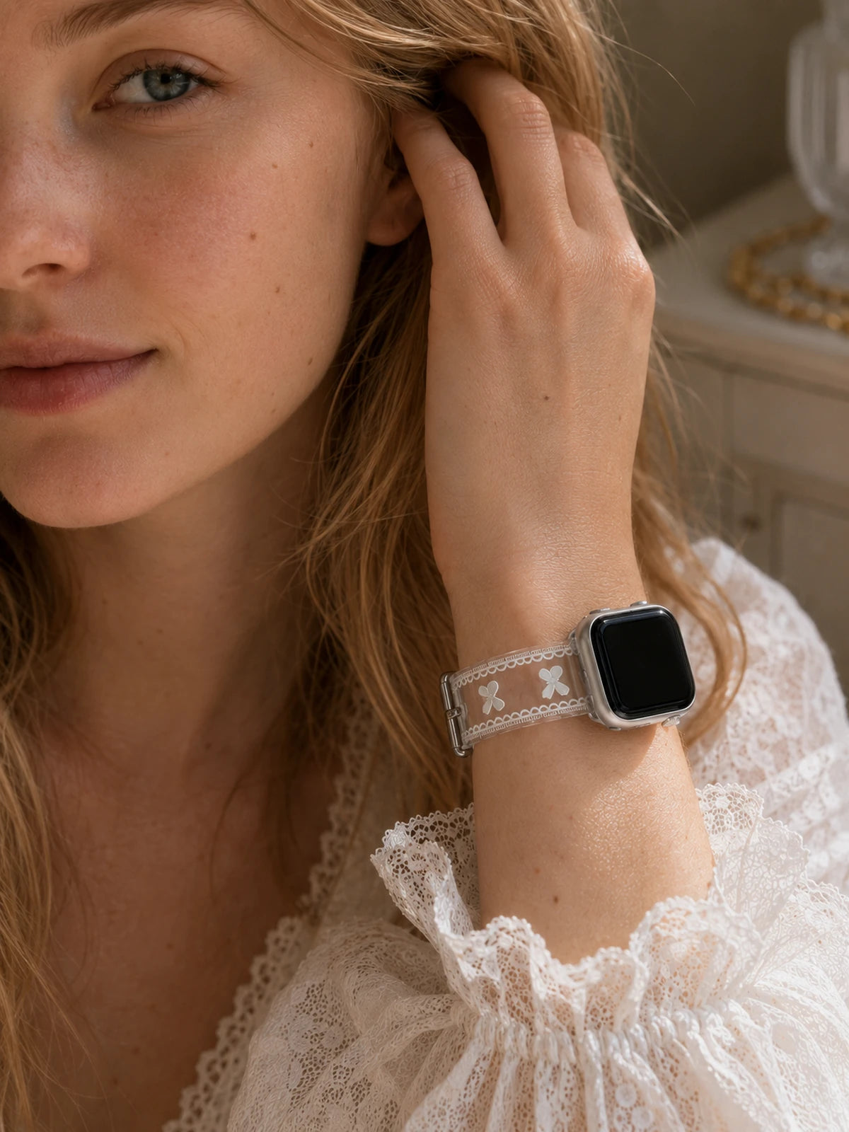 Half-face close-up of a blonde woman wearing the Odette Clear Bow Lace Apple Watch Band with a silver Apple Watch.